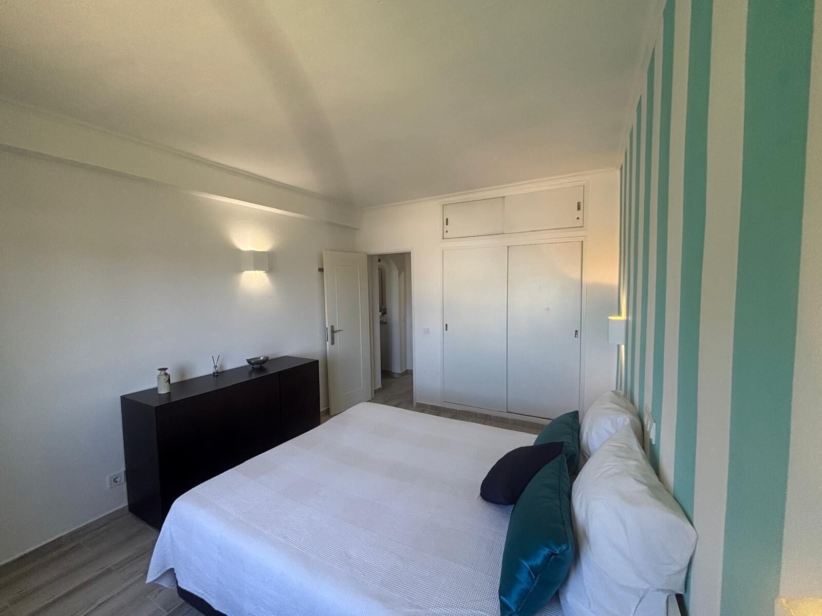 Une chambre à coucher comprenant un lit, une commode, une coiffeuse et une armoire.