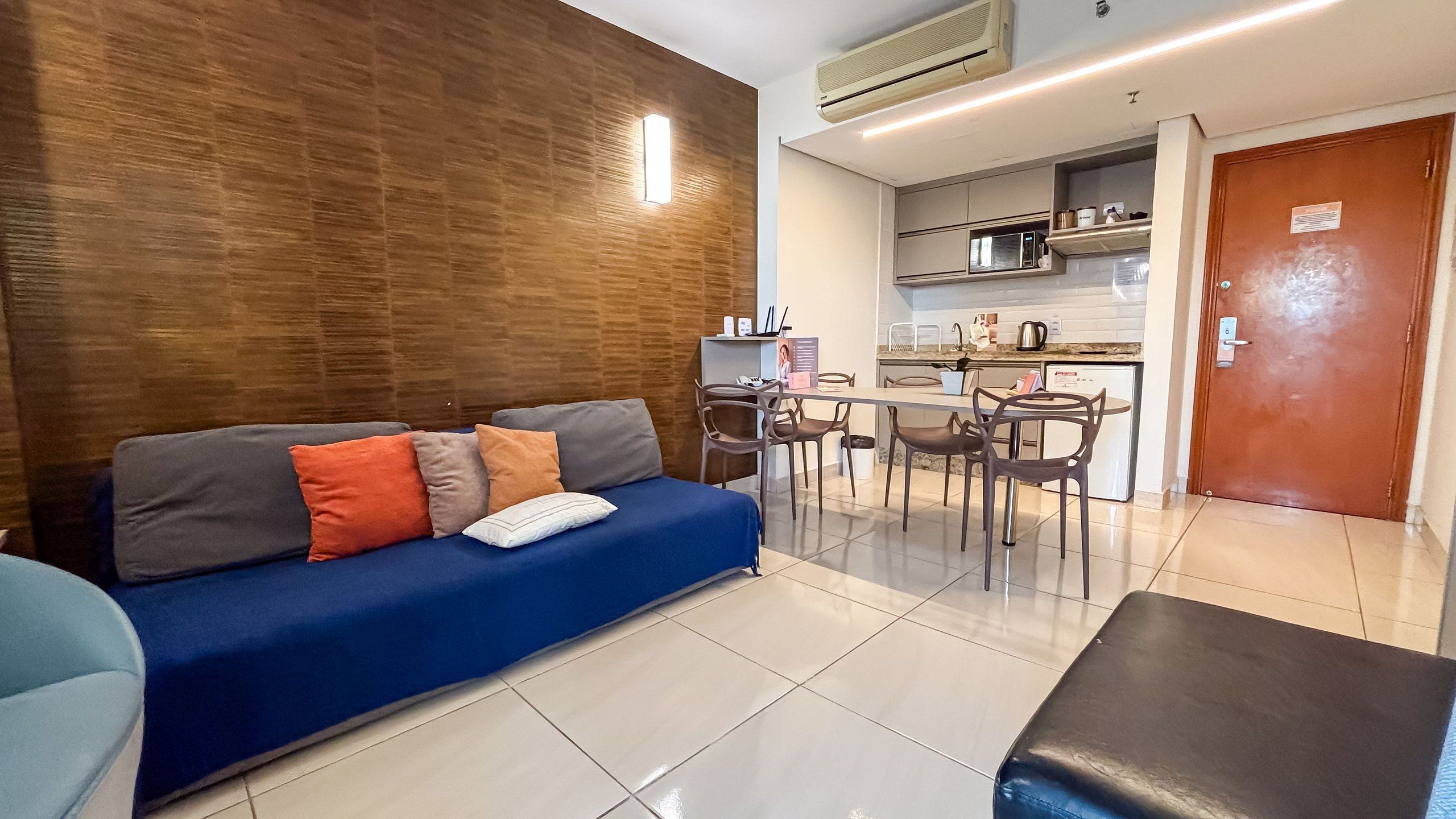 A modern living room with a sofa, a dining table with chairs, and a kitchen area.