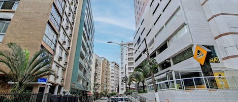 A street view with high-rise buildings, a pedestrian crossing, and a sign for 'The Hat' restaurant.