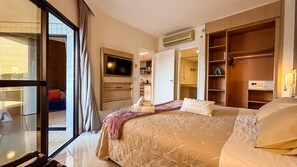 Habitació d'hotel amb un llit, televisió, armari i bany visible a través d'una porta oberta.