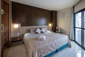 A hotel room with a large bed, two bedside lamps, a wardrobe, and a view of the city through a large window. - SHB Magnífica vista ao mar em Santos (Santos)