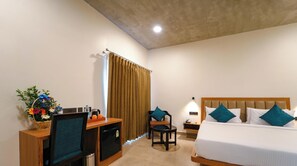 Habitación de hotel con cama, escritorio, silla y una pequeña cocina.