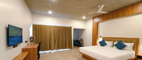 A hotel room with a bed, bedside table, TV, and curtains.