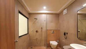 Un baño moderno con cabina de ducha de vidrio, inodoro y lavamanos.