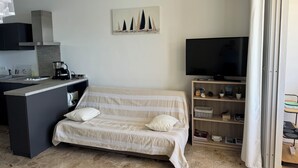 Ett sovrum med en säng, en tv, ett skrivbord med en kaffebryggare och en tavla på väggen.