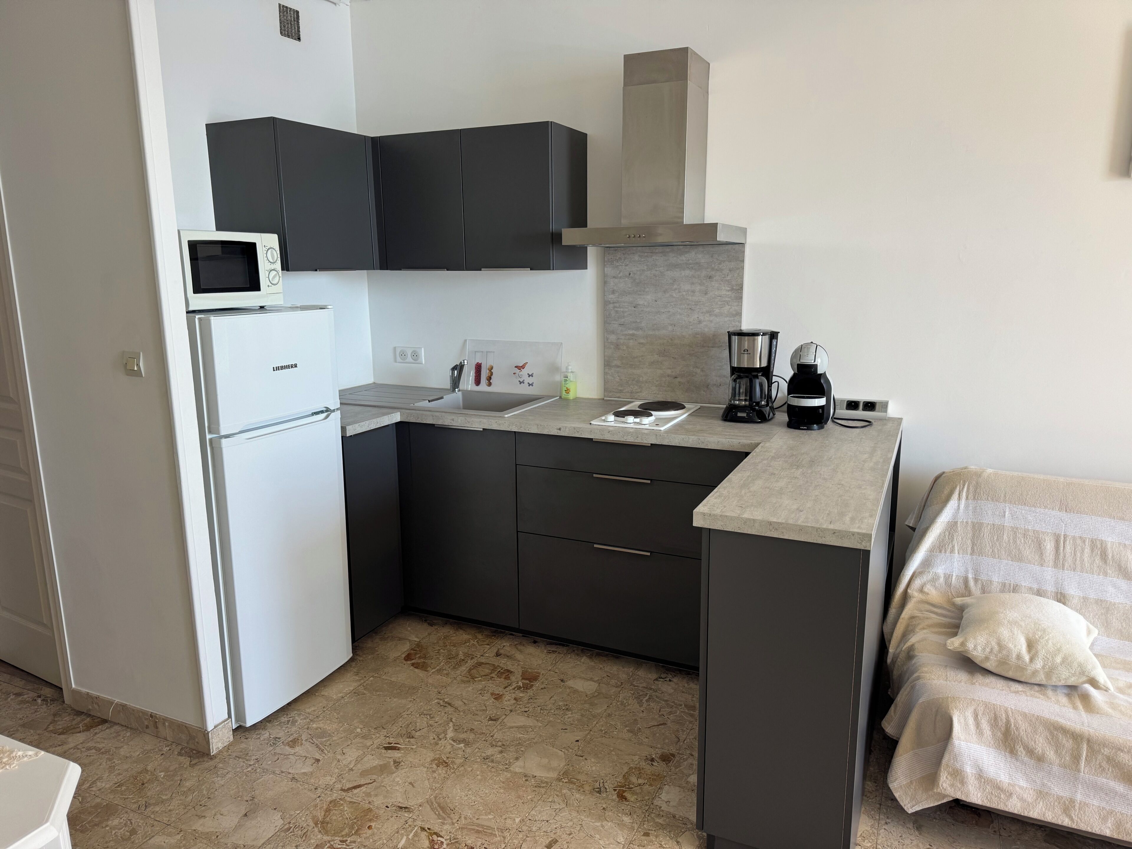 A compact kitchenette with a microwave, refrigerator, sink, and coffee maker.