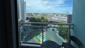 Vista da janela com uma paisagem urbana, incluindo uma estrada, edifícios e céu limpo.