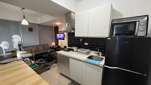 Uma cozinha moderna com micro-ondas embutido, frigorífico e televisão de ecrã plano.