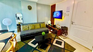 Uma sala de estar com sofá, mesa de centro, televisão e uma porta.