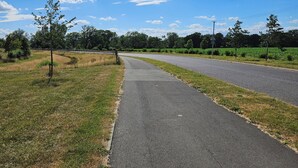 A paved pathway with grass on either side, leading to a road. - Large Private Ensuite Room + Parking,
near Gatwick (Horley)