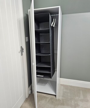 A white closet with multiple shelves and hanging space, positioned against a grey wall. - Large Private Ensuite Room + Parking,
near Gatwick (Horley)