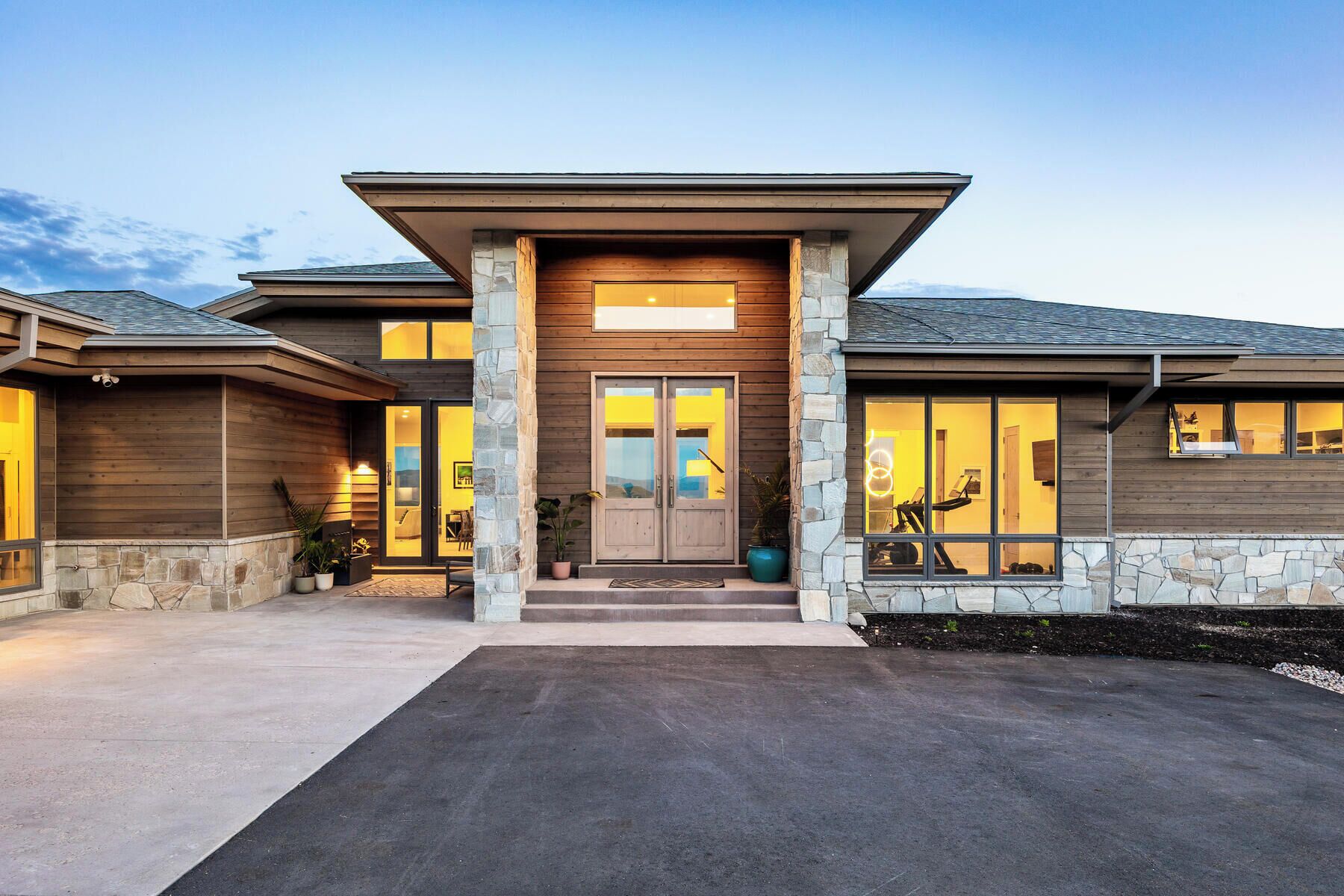 A modern two-story house with a stone facade, large windows, and a front porch.