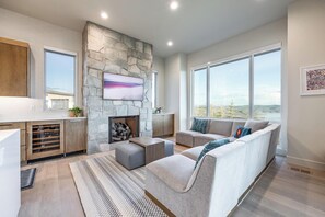 Un salon moderne avec une cheminée en pierre, un canapé et une grande fenêtre donnant sur un paysage.
