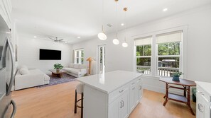 A modern kitchen with white cabinetry, a central island, and pendant lighting. - The Annabelle House (Santa Rosa Beach)