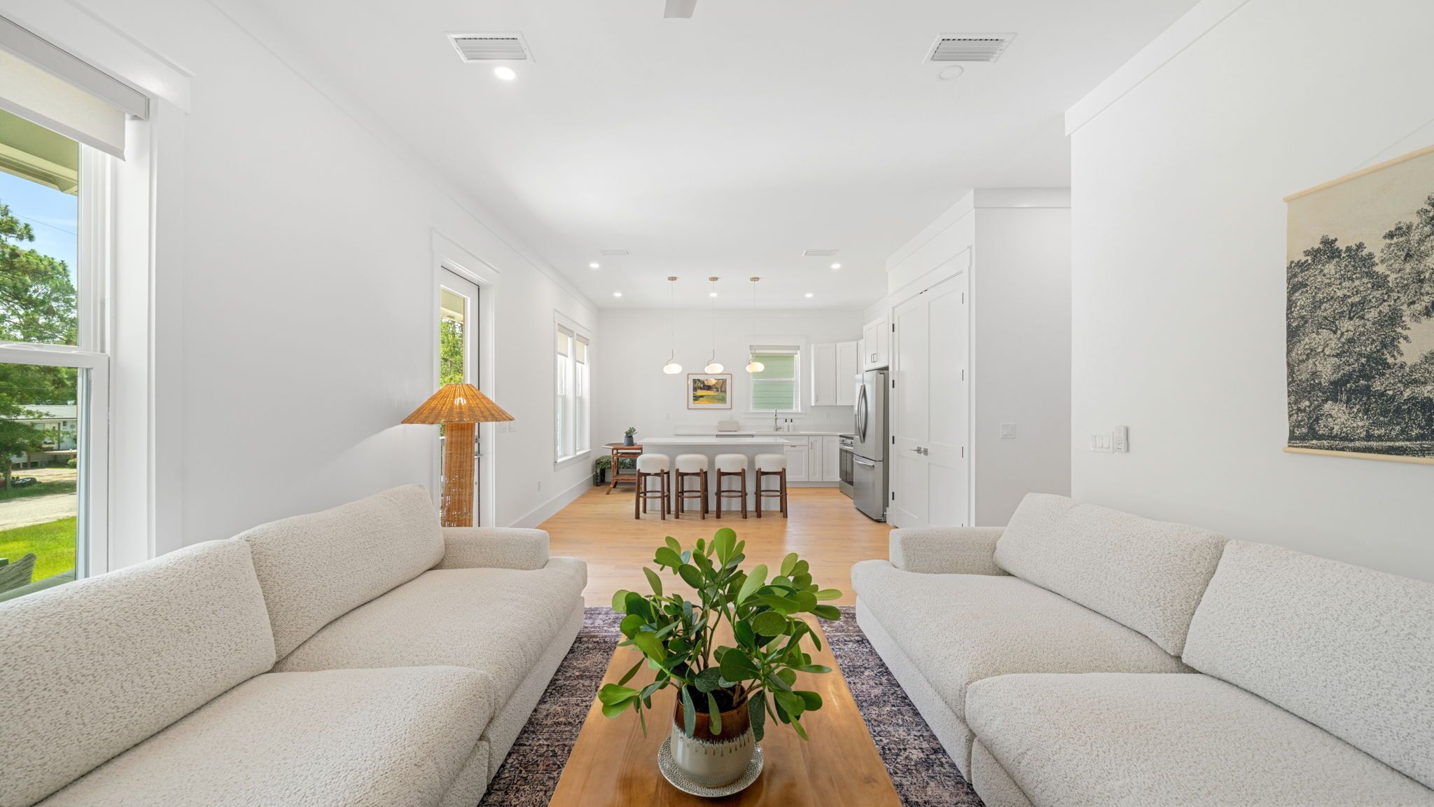 Una sala de estar moderna con un sofá, una mesa de centro con una planta y una cocina al fondo.