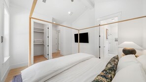 A modern bedroom with a bed, a TV, and a walk-in closet. - The Annabelle House (Santa Rosa Beach)