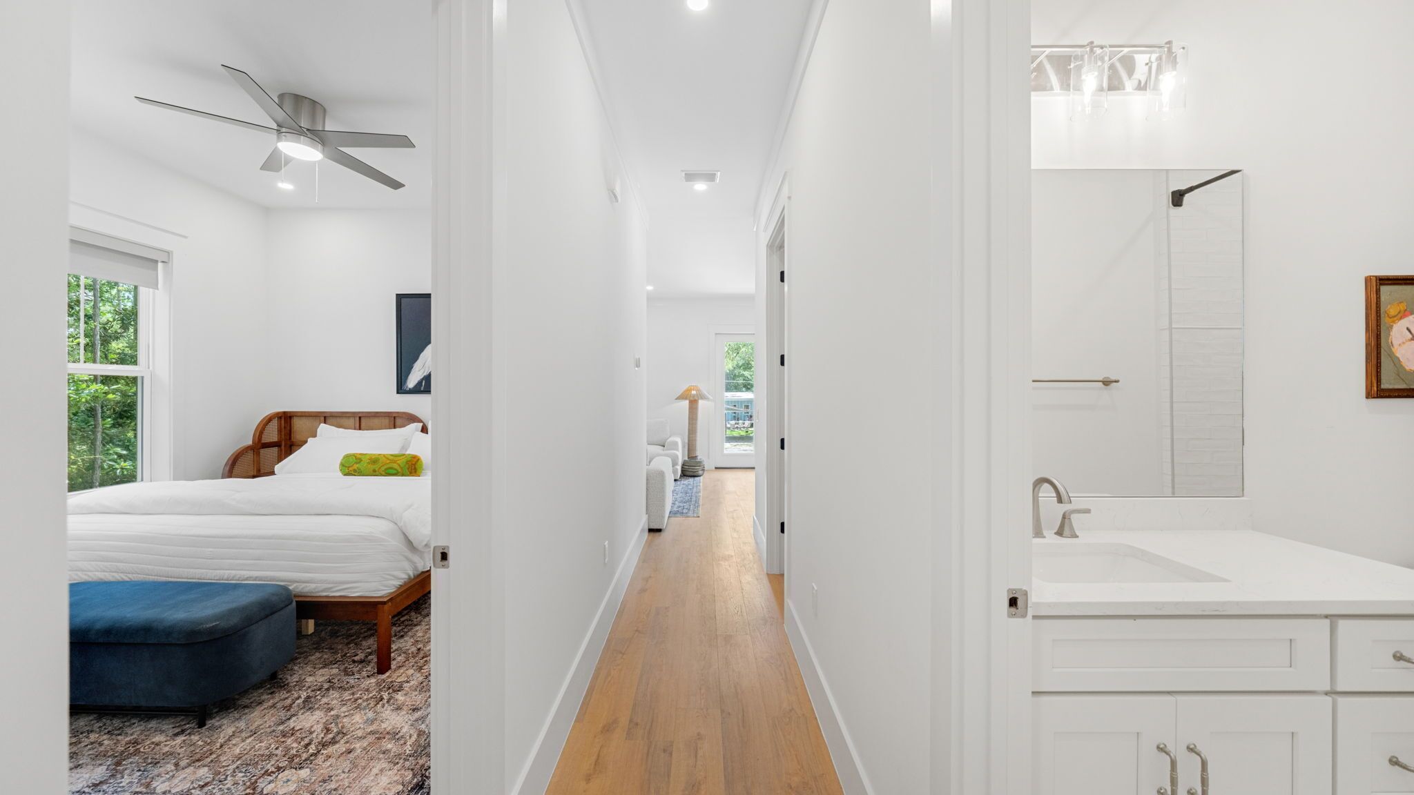 Una habitación de hotel con cama, escritorio, silla, ventana, puerta y baño con lavabo y espejo.