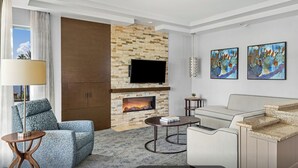 Una sala moderna con chimenea de piedra, un televisor de pantalla plana, un sofá, una mesa de centro y arte abstracto en la pared.