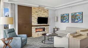 A modern living room with a stone fireplace, a flat-screen TV, a sofa, a coffee table, and abstract art on the wall. - 2 Bedroom Villa Desert Springs Resort w/Amenities (Palm Desert)