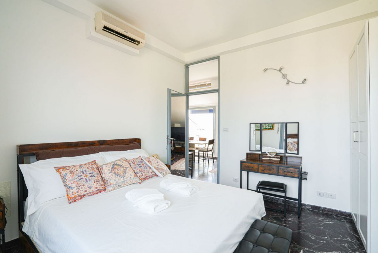 Ein Hotelzimmer mit einem Bett, einem Schreibtisch, einem Stuhl und einem durchgegangenen Tür sichtbaren Badezimmer.