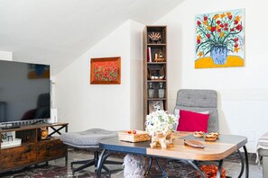 A living room with a TV, a bookshelf, a painting, and a dining table with chairs. - Piazza Statuto Terrace (Torino)