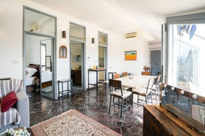 A modern interior with a dining area, a sofa, a mirror, and a large window. - Piazza Statuto Terrace (Torino)