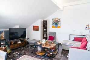 A modern living room with a flat-screen TV, a wooden coffee table, a grey sofa, and a red armchair. - Piazza Statuto Terrace (Torino)