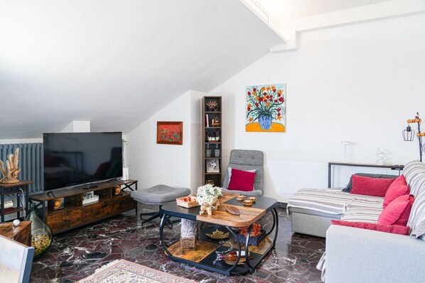 A modern living room with a flat-screen TV, a wooden coffee table, a grey sofa, and a red armchair. - Piazza Statuto Terrace (Torino)