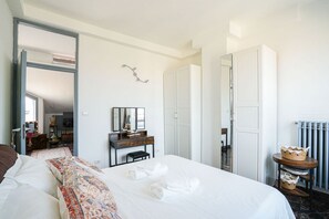 A hotel room with a bed, a dresser, a mirror, a wardrobe, and a small table with baskets. - Piazza Statuto Terrace (Torino)