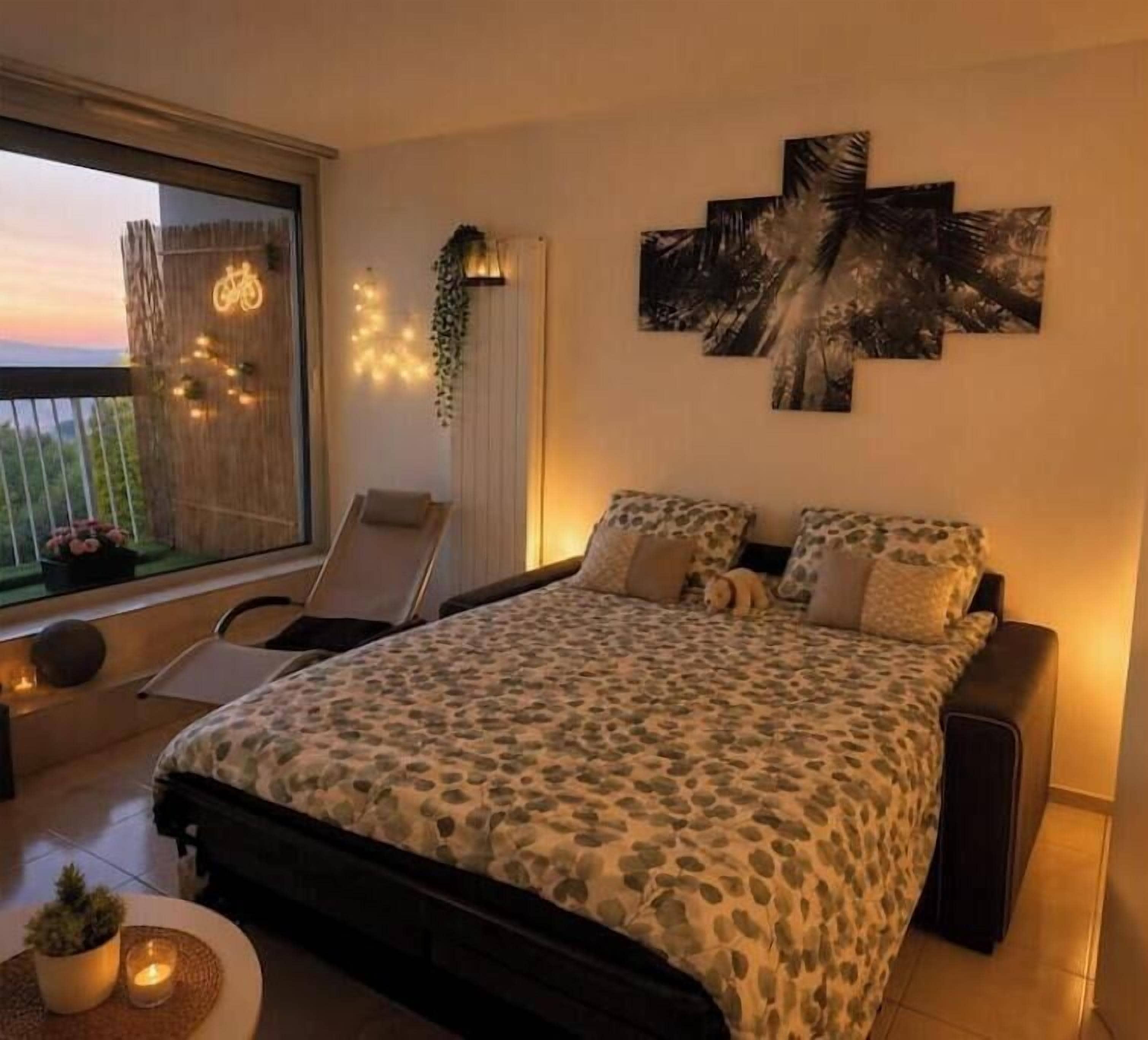 A bedroom with a bed, a chair, a window, and a wall-mounted artwork.