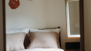 Een slaapkamer met een bed, kussens, een wandtelevisie en drie decoraties aan de muur.