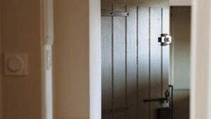 Een modern interieur met een houten vloer, een deur met metalen frame en een hanglamp.