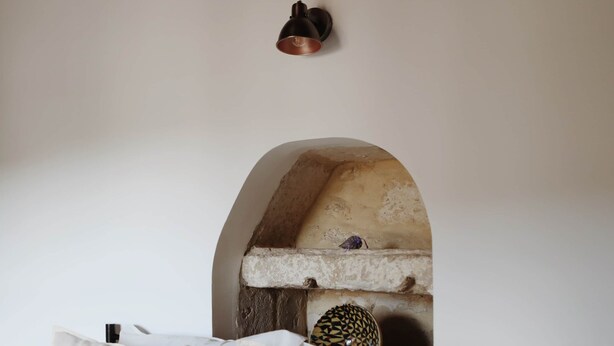 A bed with white linens, a stone archway, and a small shelf with decorative items. - La Valette Boutique - La Maison (Sanilhac-Sagriès)