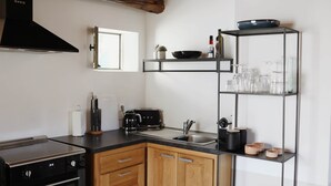 A modern kitchen with a stove, oven, sink, and wooden cabinets. - La Valette Boutique - La Maison (Sanilhac-Sagriès)