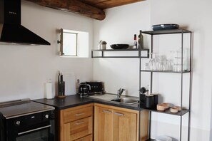 A modern kitchen with a stove, oven, sink, and wooden cabinets. - La Valette Boutique - La Maison (Sanilhac-Sagriès)