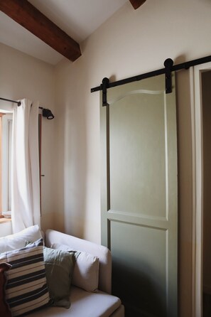 Ein Zimmer mit einer Couch, einer Schiebetür und einem fenster mit Vorhängen.