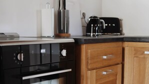 Una cocina con horno negro, armarios de madera y una encimera con utensilios de cocina.