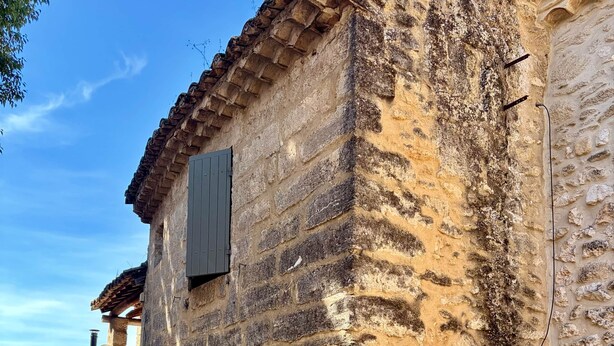 Un edificio de piedra con una puerta y una ventana, rodeado por un camino de grava.