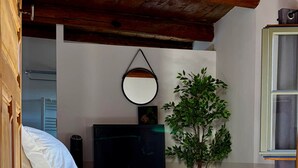 Una cama con colchón blanco, una sola almohada y una pequeña planta en maceta a su lado.