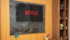 Ein an der Wand befestigter Fernseher mit einer Holzpaneel-Optik und Marmorstruktur.