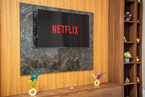 A television mounted on a wall with a wooden panel and a marble-like texture. - Modern apartment at Hivernage marrakech Near Train Station (marrakech)