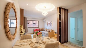 Ein modernes Wohnzimmer mit Esstisch, Sofas, einem großen Spiegel und einer dekorativen Vase.