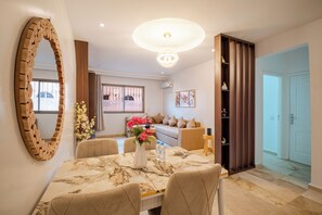 A modern living room with a dining table, sofas, a large mirror, and a decorative vase. - Modern apartment at Hivernage marrakech Near Train Station (marrakech)
