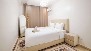Ein modernes Schlafzimmer mit Bett, Nachttischen, einem Spiegel und einer Klimaanlage.