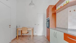 A kitchen with white cabinets, a wooden table, and a chair. - MOD1 - BEAUTIFUL APARTMENT WITH A TERRACE (Milano)