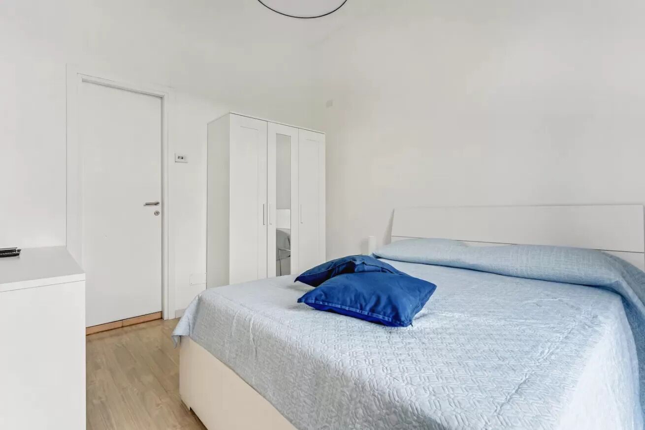 A bedroom with a bed, a wardrobe, and a door.