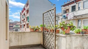 A balcony with potted plants, a metal gate, and a view of neighboring buildings. - MOD1 - BEAUTIFUL APARTMENT WITH A TERRACE (Milano)