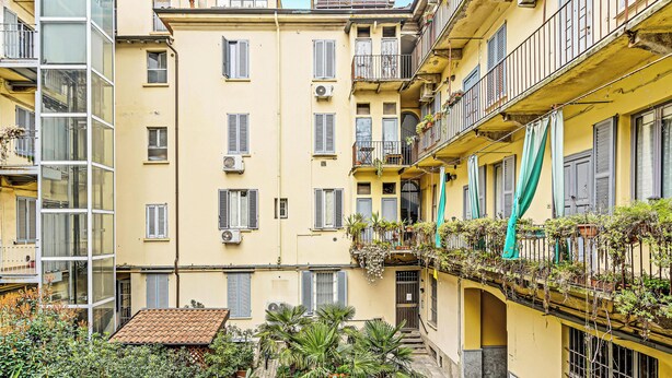A multi-story building with balconies, air conditioning units, and a variety of potted plants. - MO10 Pleasant Stay x4 in Milan (Milano)