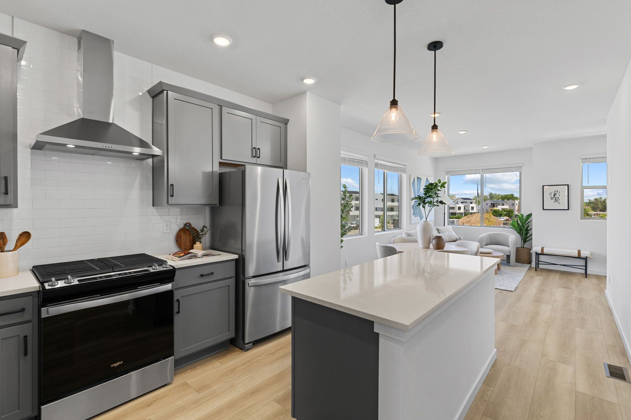 A modern kitchen with stainless steel appliances, grey cabinets, and a large island.