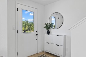 A white door with a window, a white console cabinet with drawers, a round mirror, and a potted plant. - Brand-New 3-Bedroom Townhome Near Golden, Boulder & Ralston Creek Trail. (Arvada)
